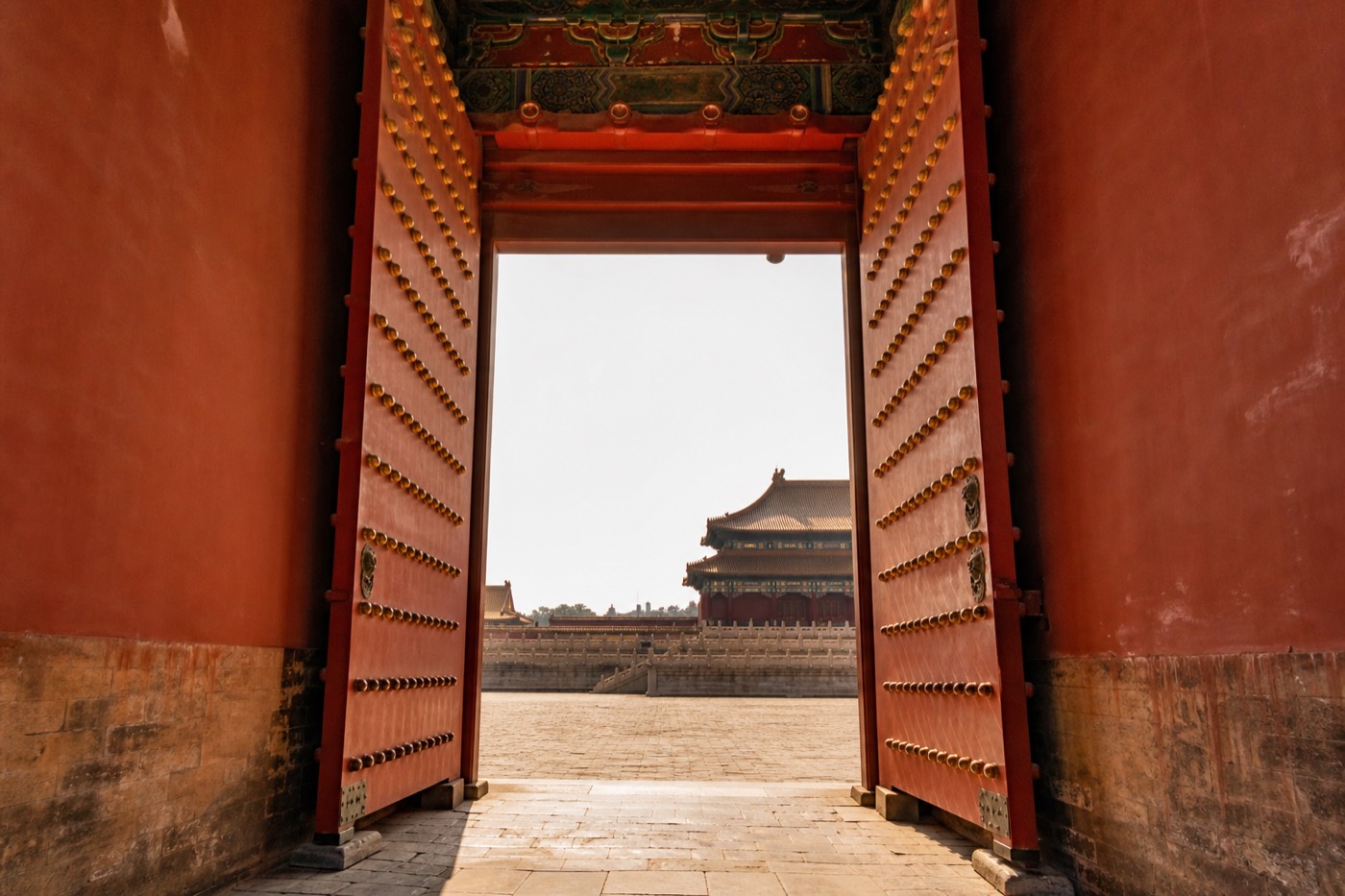 An open gate into the Forbidden City in daylight, visitors passing through