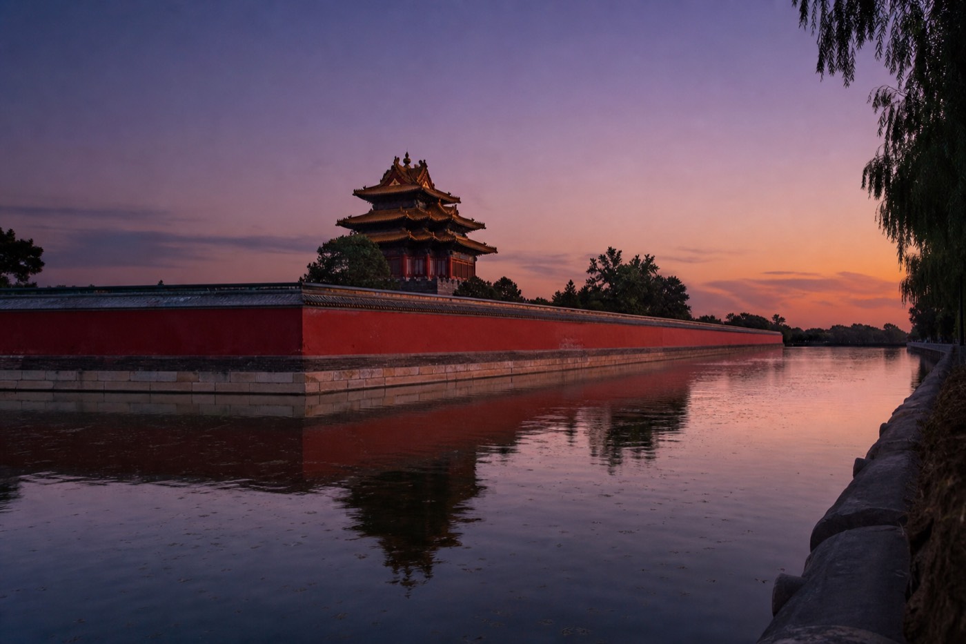 The Forbidden City's high red walls glowing at dusk near one of the corner watchtowers