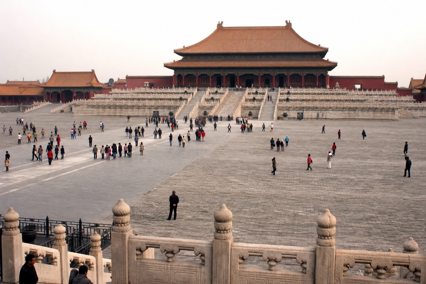 Distant figures dwarfed by the scale of a Forbidden City courtyard and hall